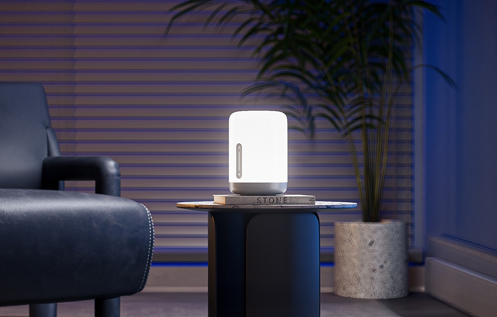 Lamp shining bright light on a table in a modern living room with a potted plant in the background