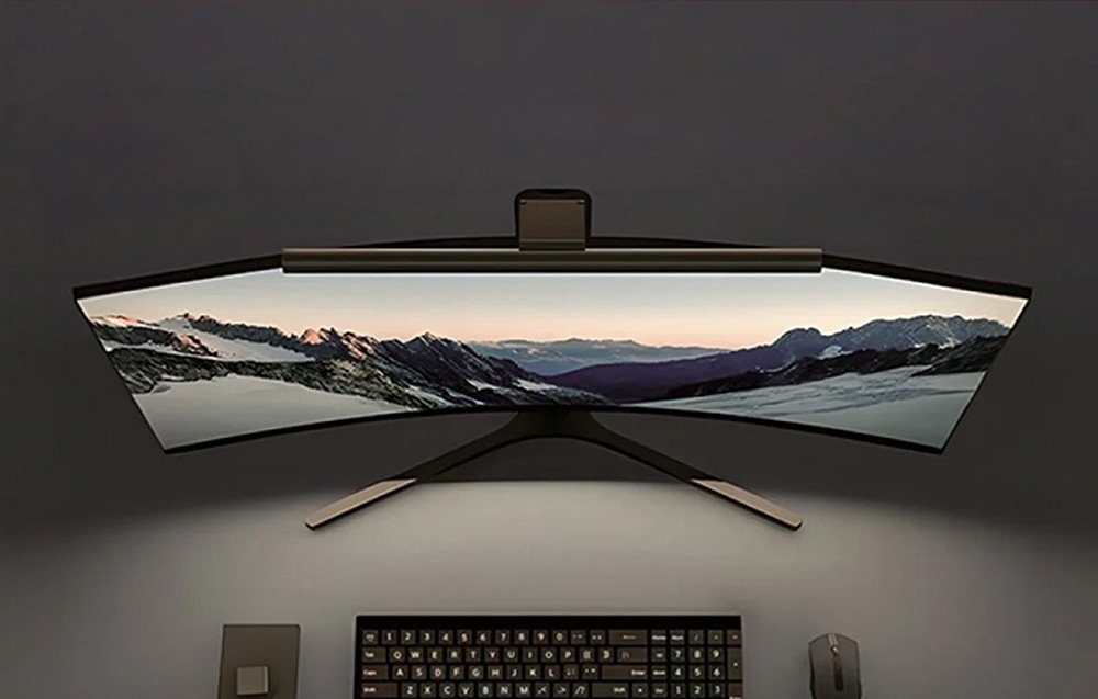 Top view of a curved monitor with a Yeelight lamp mounted, with a keyboard and mouse in front