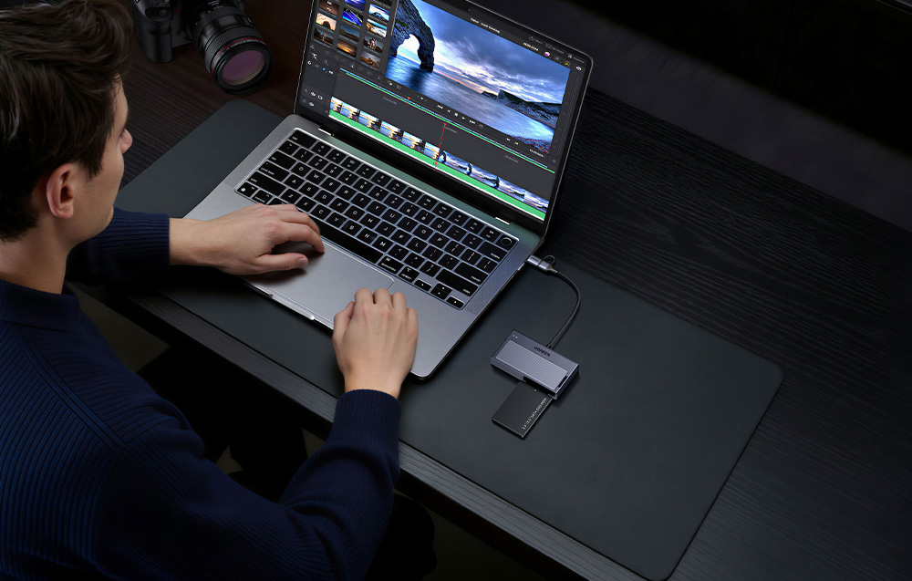 Mężczyzna pracujący na laptopie, do którego podłączona jest obudowa na dysk Ugreen z włożonym dyskiem SSD