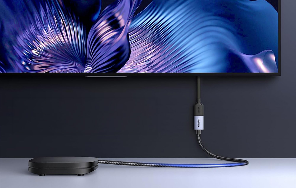 Czarna przystawka Smart TV połączona kablem i adapterem Ugreen do telewizora na ścianie