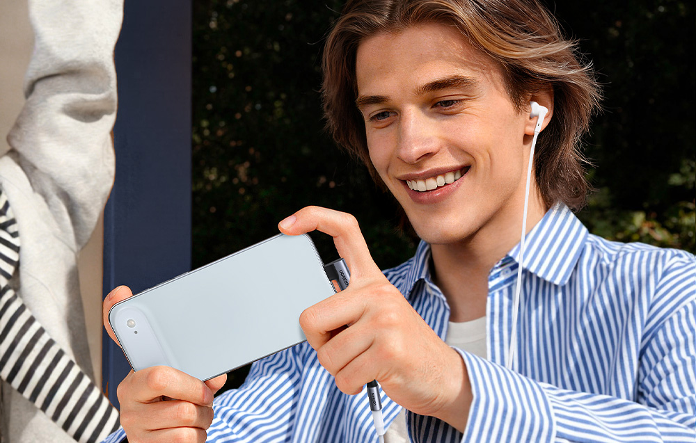 Mężczyzna gra na telefonie podłączonym do słuchawek za pomocą kątowego adaptera audio