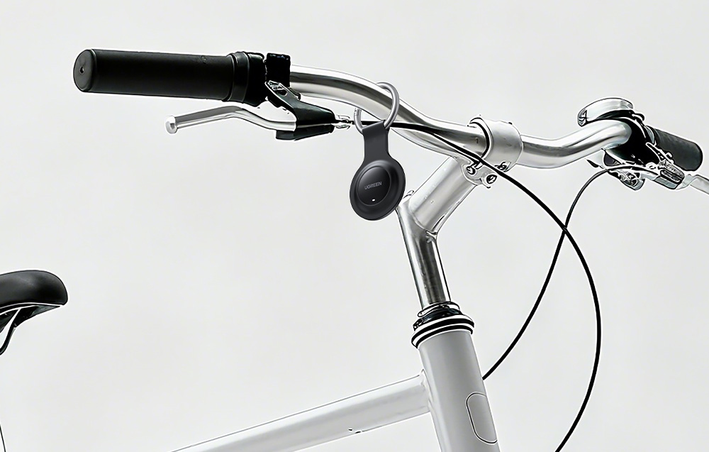 Black Ugreen locator hanging on the handlebars of a white bicycle