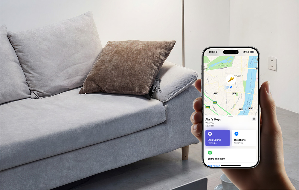 Person holding a phone with an app locating keys hidden behind a pillow on a couch