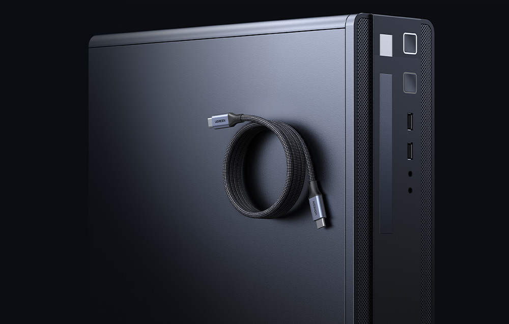 Czarny kabel USB-C marki Ugreen zwinięty w pętlę na tle obudowy komputera stacjonarnego