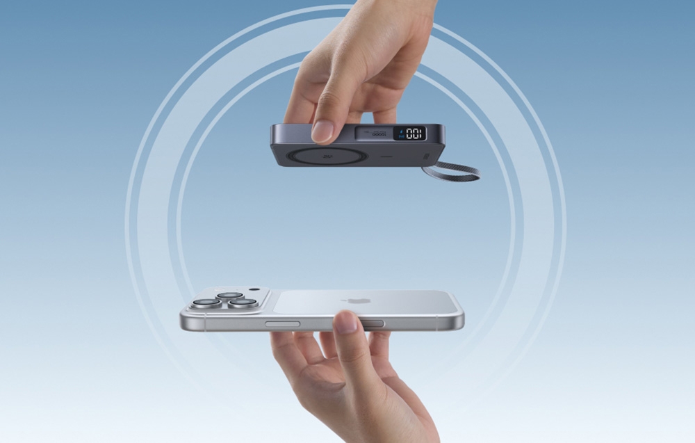 Two hands bringing together an Apple iPhone smartphone and a gray Ugreen wireless power bank with LED display