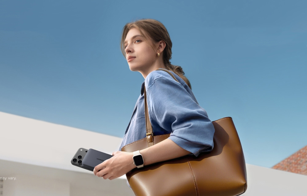Woman with a brown bag holding a smartphone connected magnetically to the Ugreen power bank