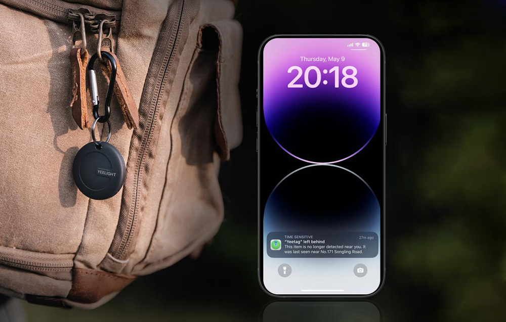 Lokalizator przypięty do plecaka obok smartfona z powiadomieniem o utraconym połączeniu z urządzeniem