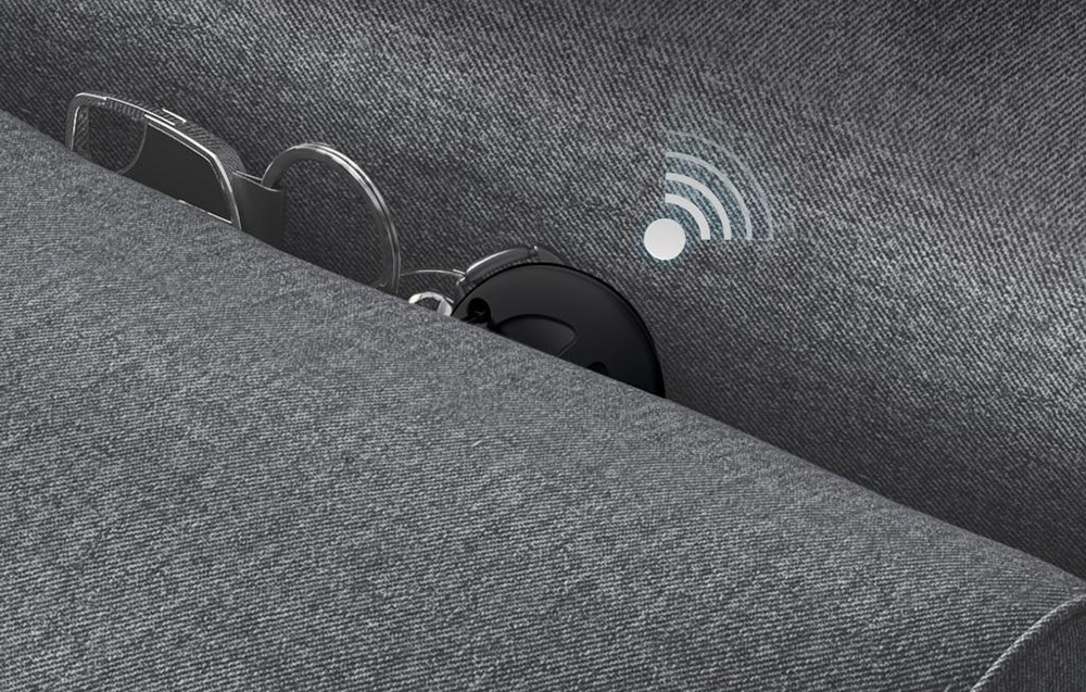 Lokalizator i klucze częściowo widoczne w szczelinie kanapy z ikoną sygnału lokalizacji