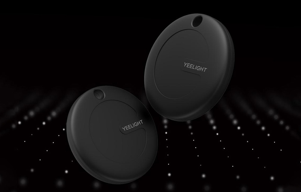 : Dwa czarne lokalizatory YEELIGHT pokazane na ciemnym tle z efektem świetlnym