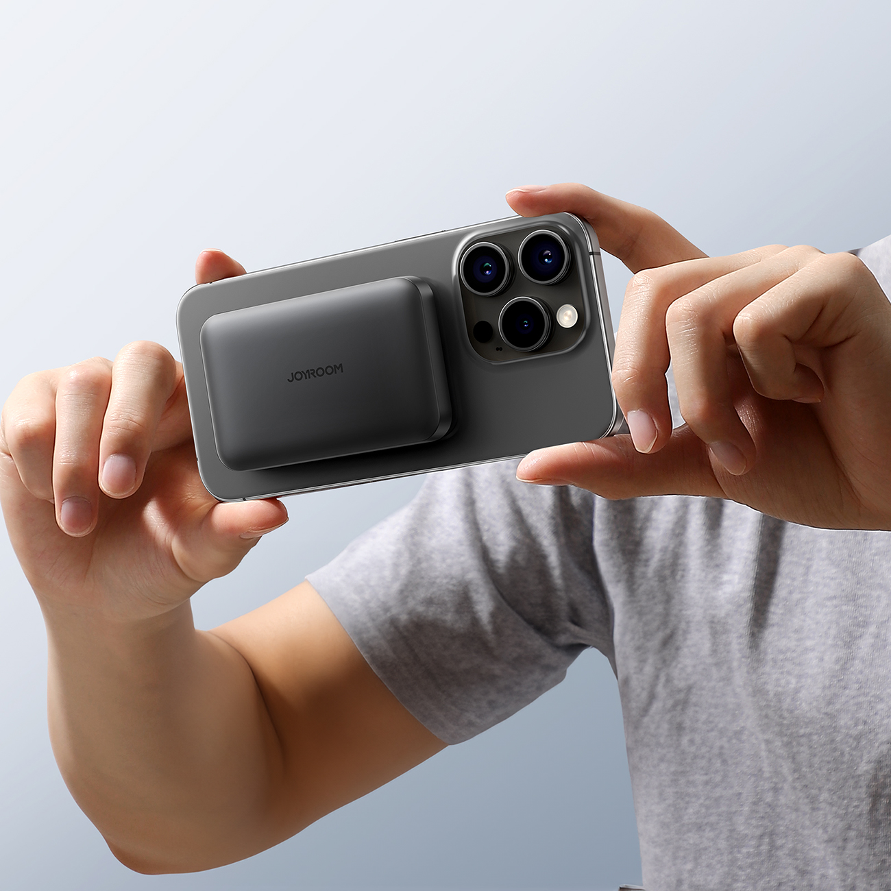 Mężczyzna robiący zdjęcie za pomocą iPhone z przyczepionym powerbankiem indukcyjnym Joyroom JR-W020 Mini